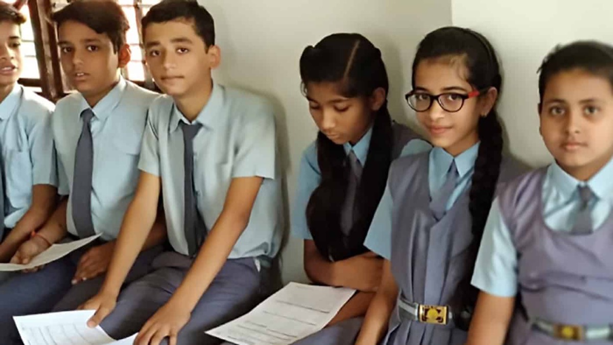 Schoolchildren in uniform seated with worksheets in a classroom