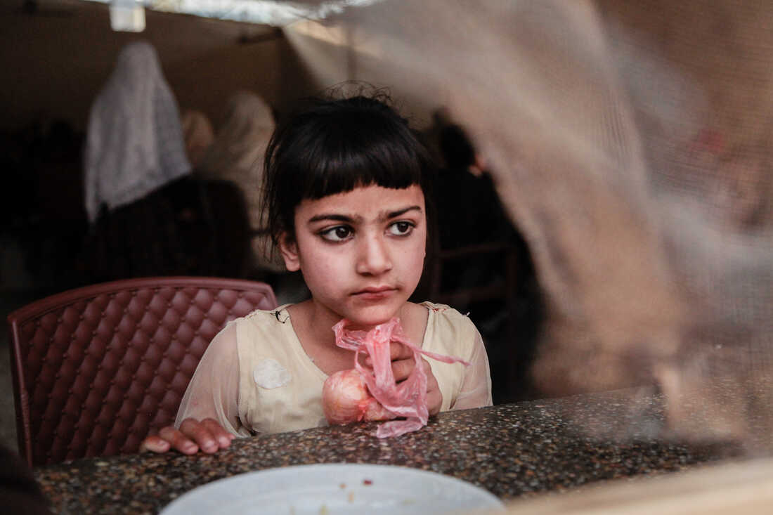 A young girl seated at a table during a community meal